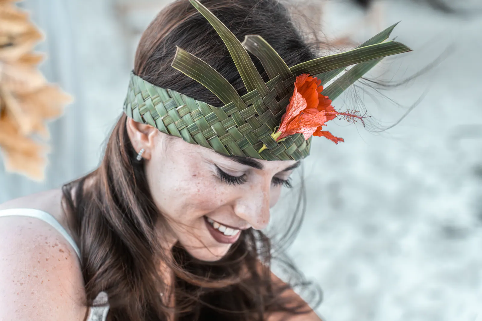 Bride smiling, close-up of her palm-leaf crown with a red hibiscus