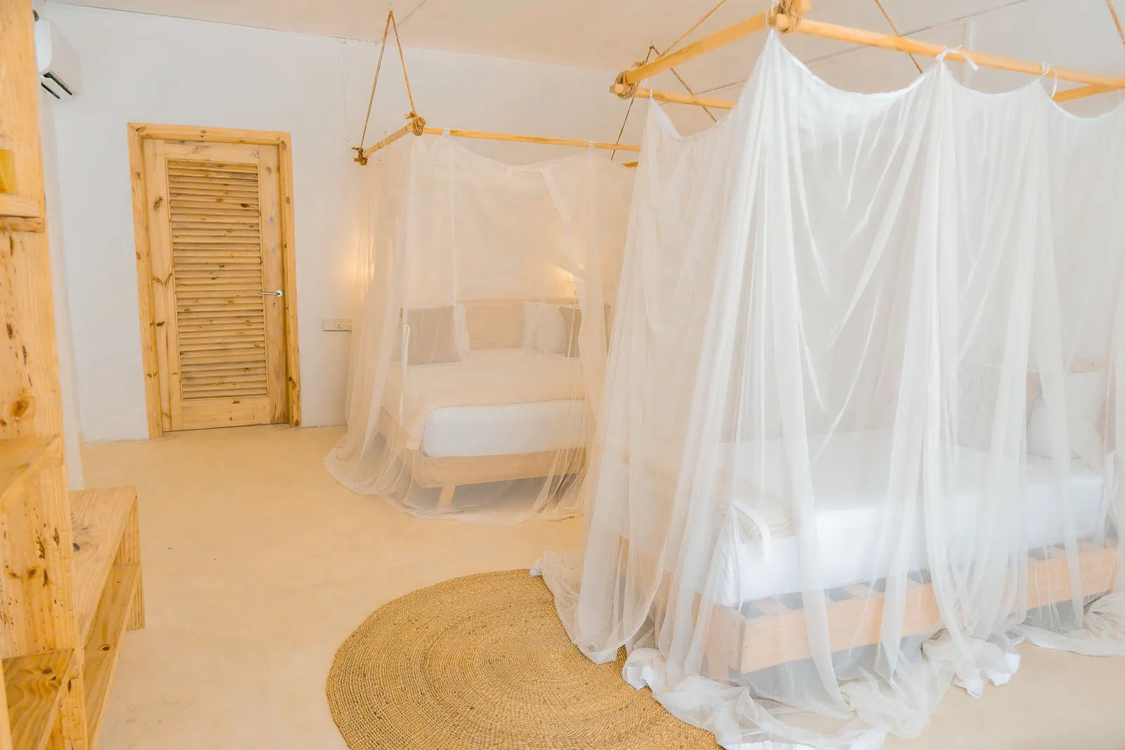White boutique hotel room with a canopy bed and a round jute rug